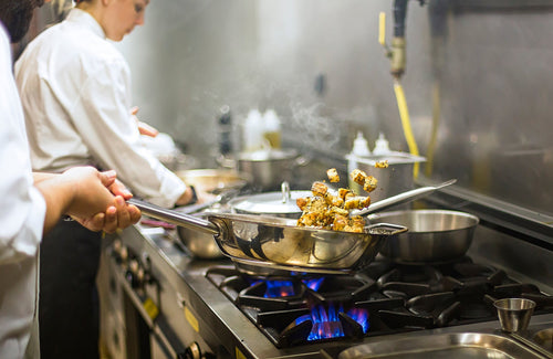 Chef preparing food on a commercial cooktop