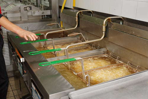 Chef frying food in a commercial floor standing deep fryer 