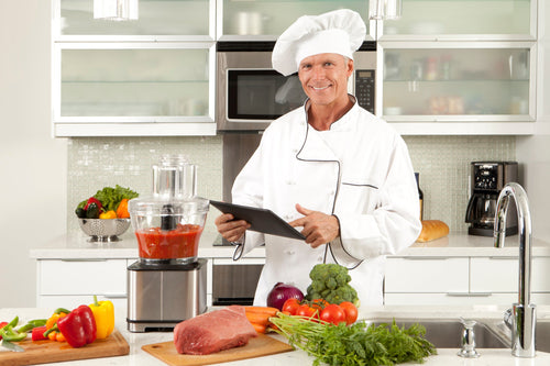 Chef showcasing a commercial food processor with a mix of ingredients inside.